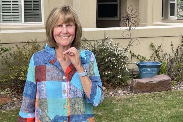 A woman holds a medallion she wears as a necklace.