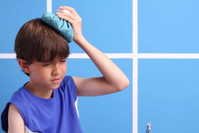 Boy with basketball holding bag of ice on head