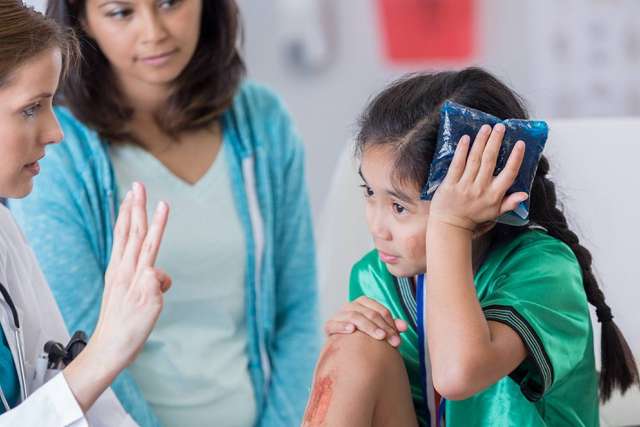 Little girl and mother at a doctors appointment being helped by a medical professional 