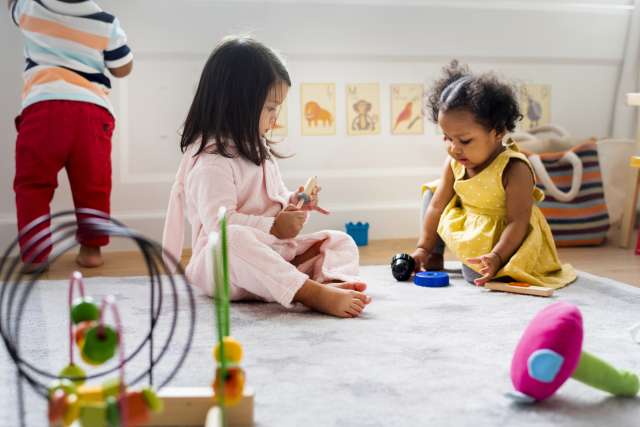 Two children playing with toys on the carpet