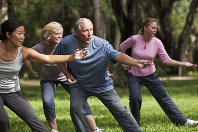 Diverse group of people doing tai chi in park