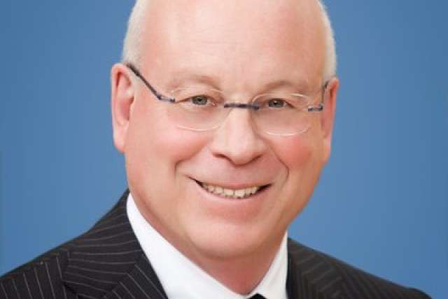 Dr. Michael Steinberg, wearing glasses and a dark striped suit, smiling in a professional headshot.
