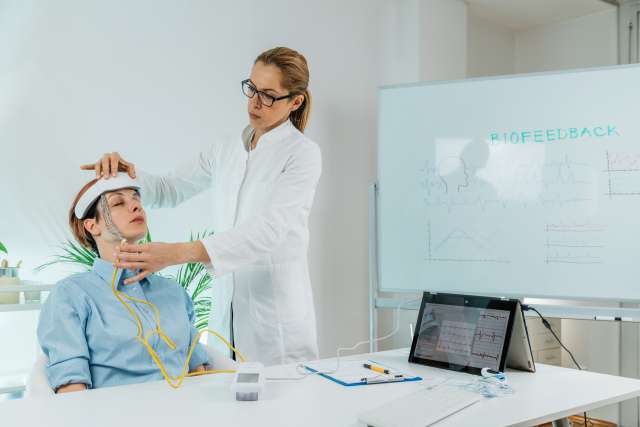 Therapist monitoring brain waves using scalp sensors placed onto a client’s head