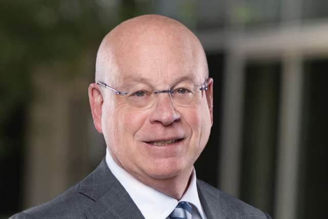 Dr. Michael Steinberg, wearing glasses and a dark suit with striped tie, smiling in a professional headshot.