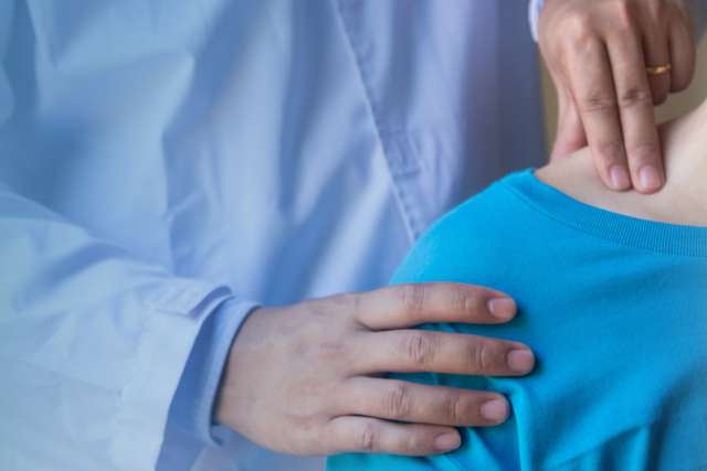 Side view close-up of a doctor's hand checking neck bone