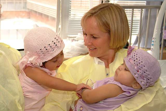 Two Marias as babies wearing pink knit hats
