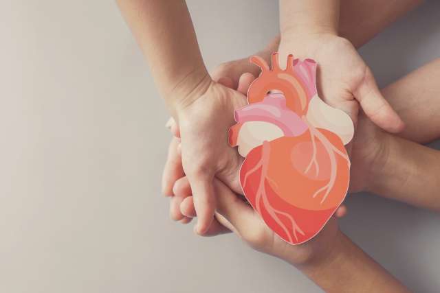 Several hands holding a cutout image of a heart