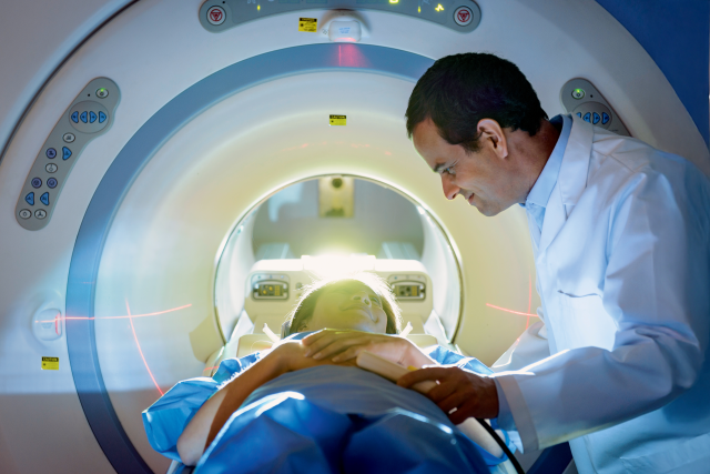 A doctor assists a patient in a CT scan machine.