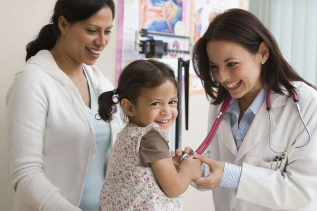 Female doctor looks into the camera and smiles as she helps a pediatric cancer patient