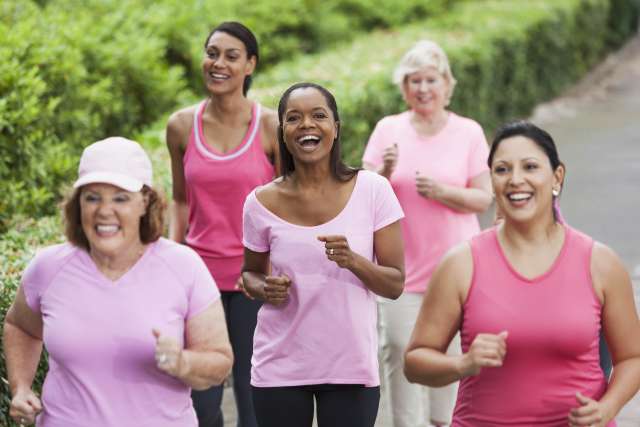 Group of breast cancer survivors wearing pink shirts, jogging together