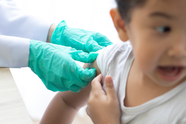 A kid having a vaccine administered by a physician
