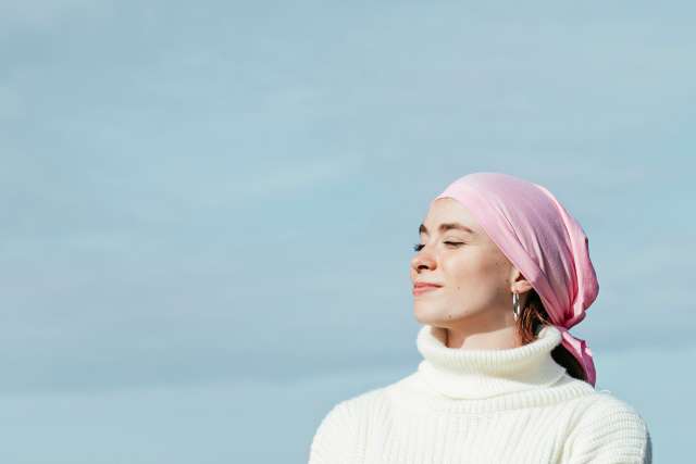 Woman with a pink headscarf staring off into distance.