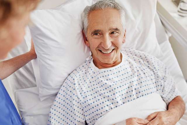 Elderly man smiling on hospital bed