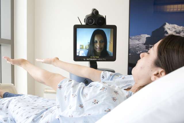 Patient in bed communicating via monitor with doctor