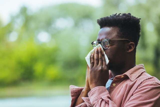 Man sneezing outside from allergy