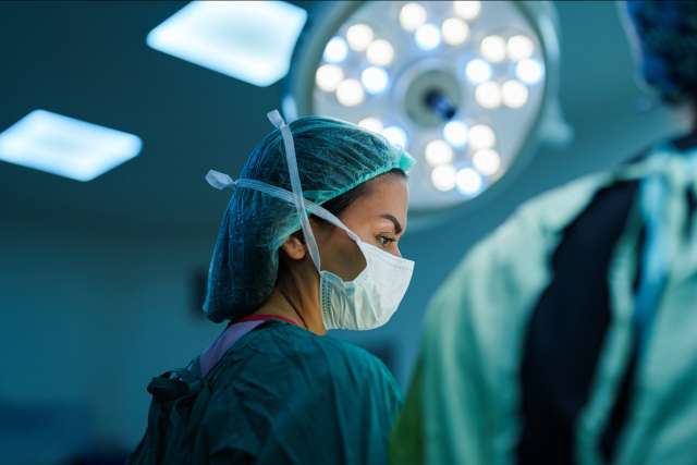 Surgeons in scrubs and masks preparing for a procedure in an operating room.