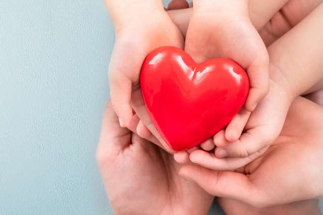 The adult and the child holding red heart.