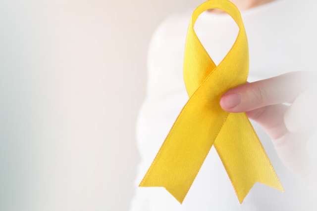 Young female holding yellow gold ribbon awareness for childhood cancer.