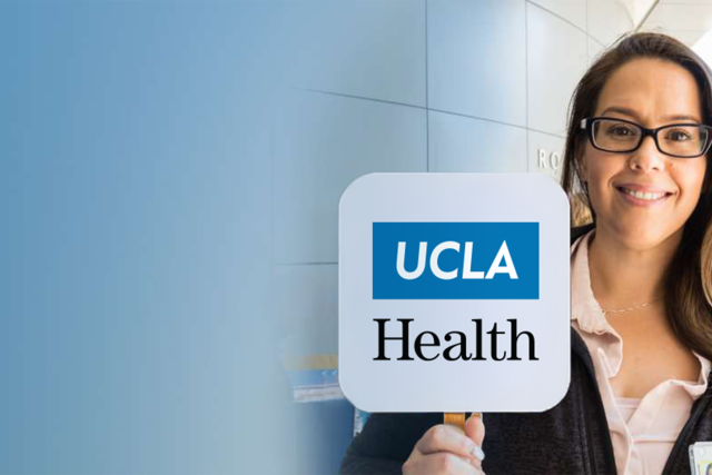 A woman holding up a sign that says UCLA Health