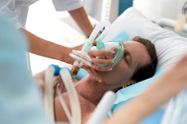 Middle aged man getting mechanical ventilation in hospital using respiratory equipment
