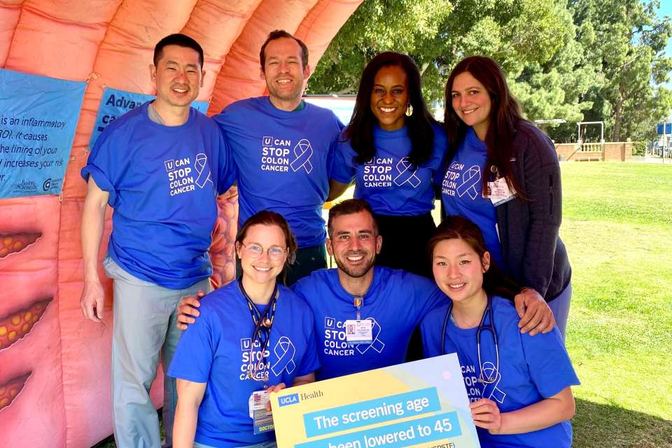 A group of six people in blue shirts poses inside a large inflatable colon.