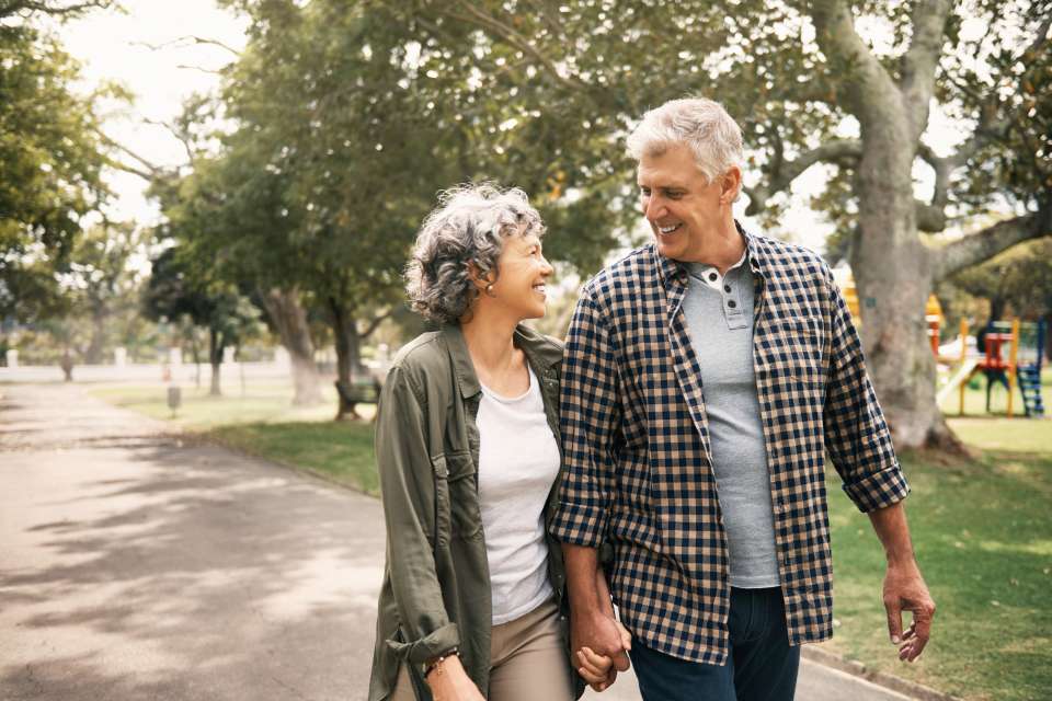 Older couple walking outside on a sunny day and holding hands
