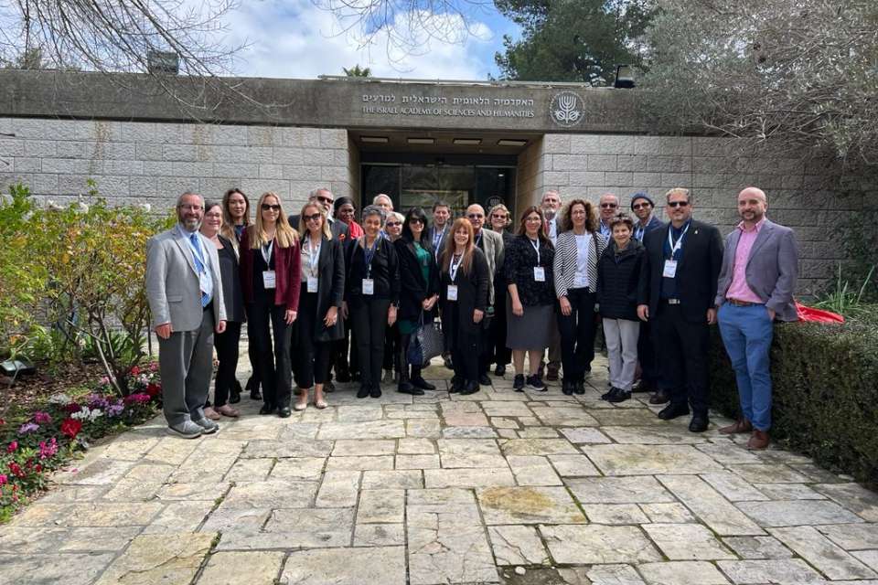 23 diverse scholars standing in front of the Israel Academy of Sciences and Humanities during an academic wartime learning mission to Israel.