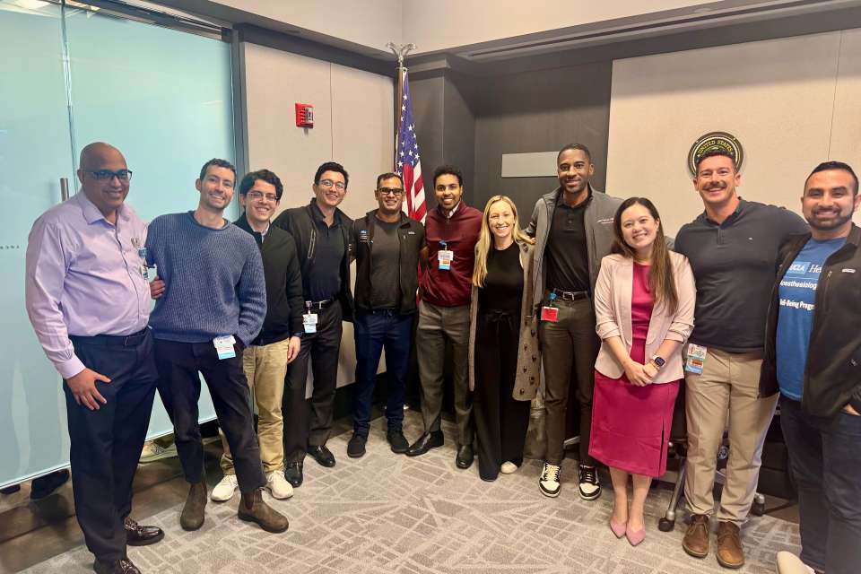 A group of people posing together in a conference room with an American flag.