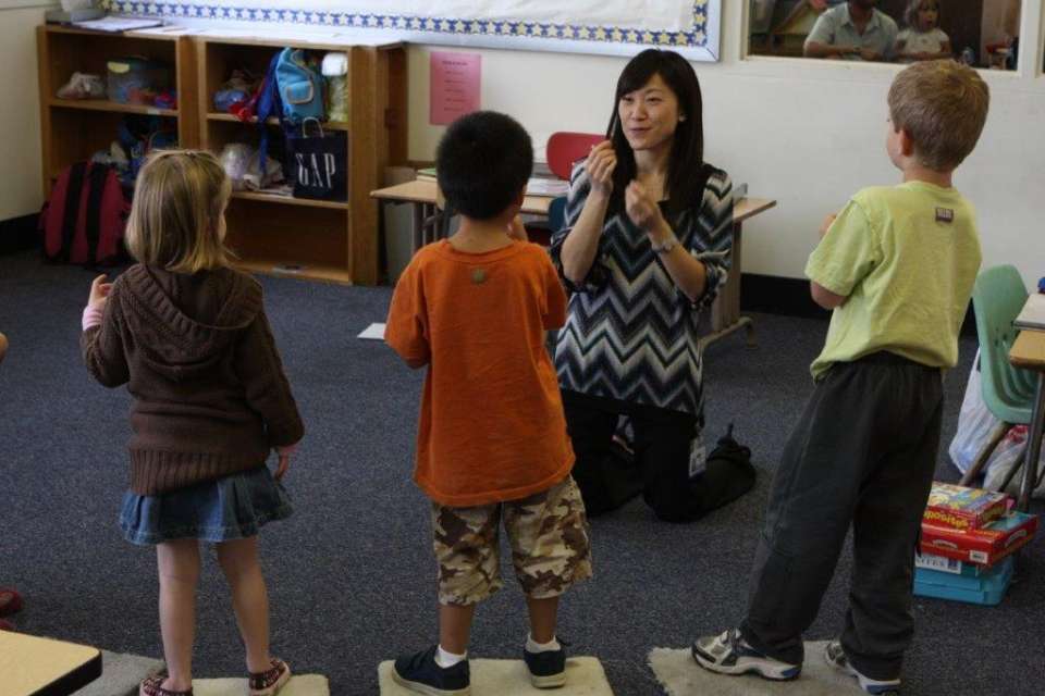 Teacher kneeling in front of class with students