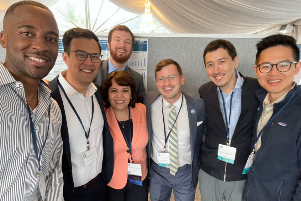 Group photo of DAPM members, smiling at an annual meeting. They are wearing professional attire and name tags.