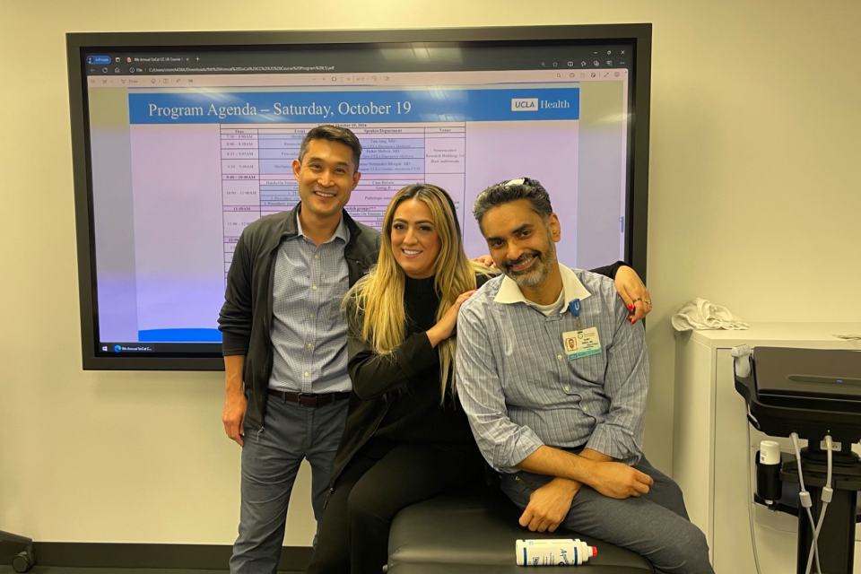 Three participants of the 9th Annual Southern California Critical Care Ultrasound conference hugging and sitting together in front of the classroom.