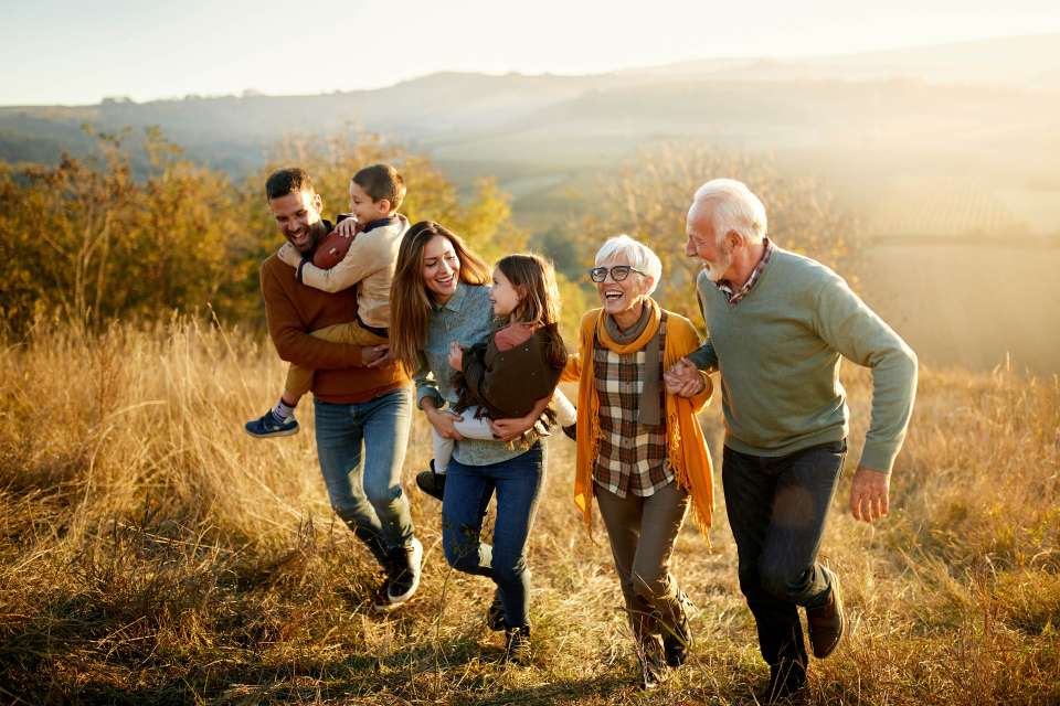 Family walking up hill: multigenerational group climbing a grassy slope at sunset