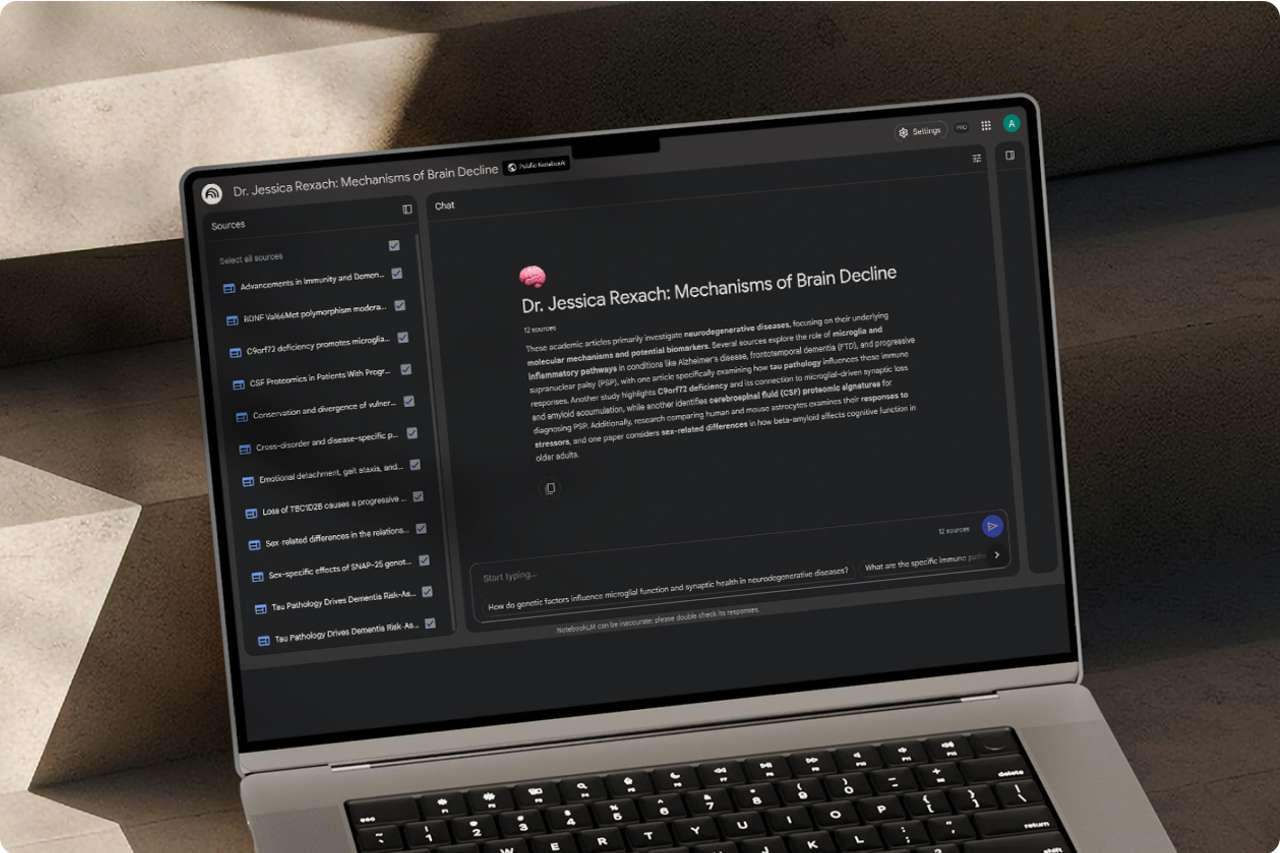 A high-angle view of a gray laptop in a dark, minimalist setting. The screen shows a Google Gemini interface with a block of text.