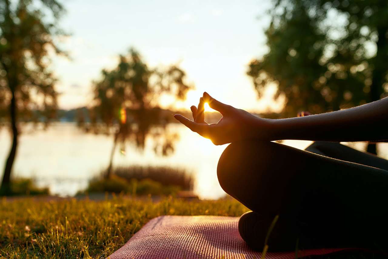 Woman Meditating by the Beach with Sun in Background