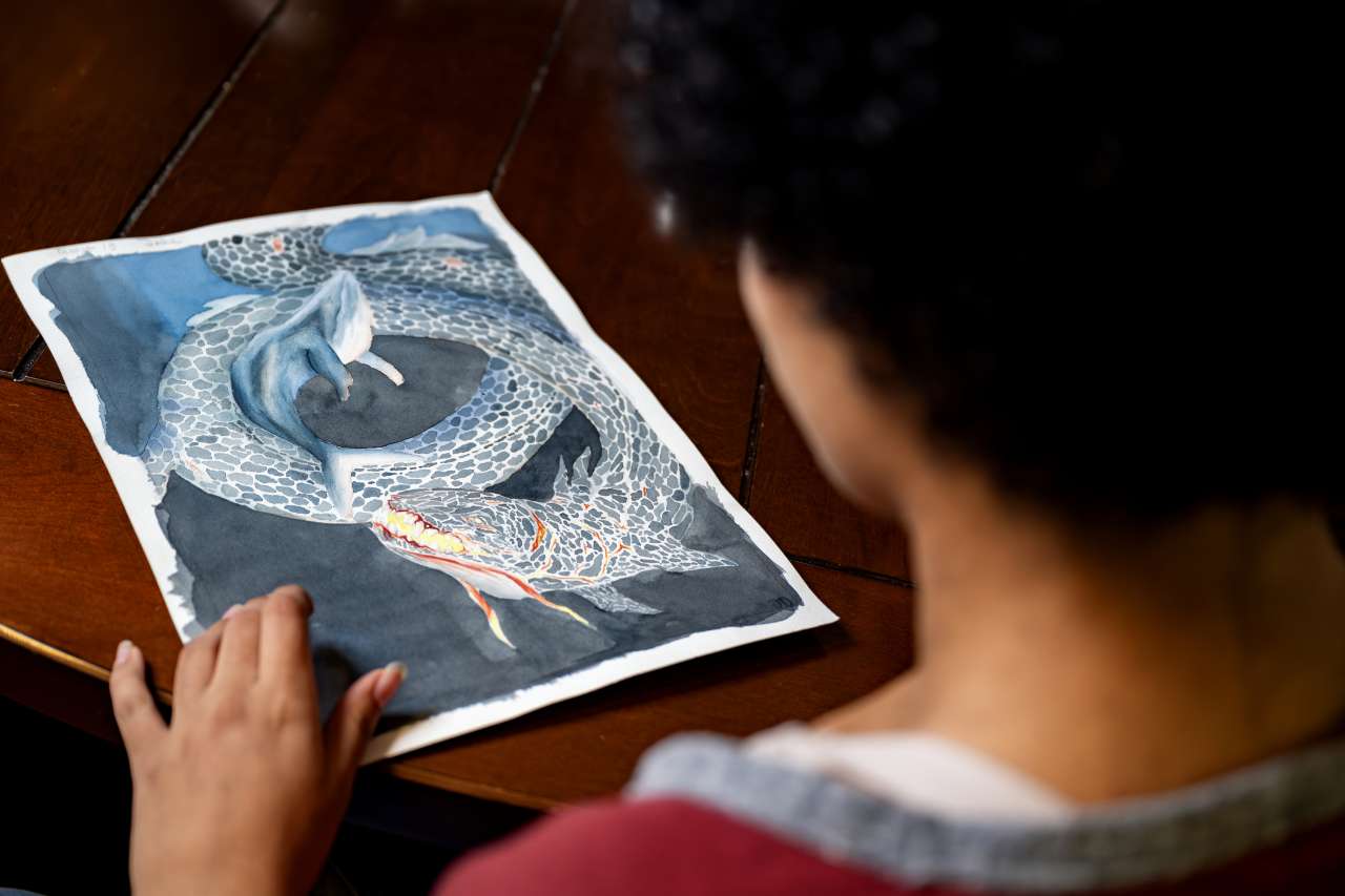 Jade Wilson looks at her watercolor painting