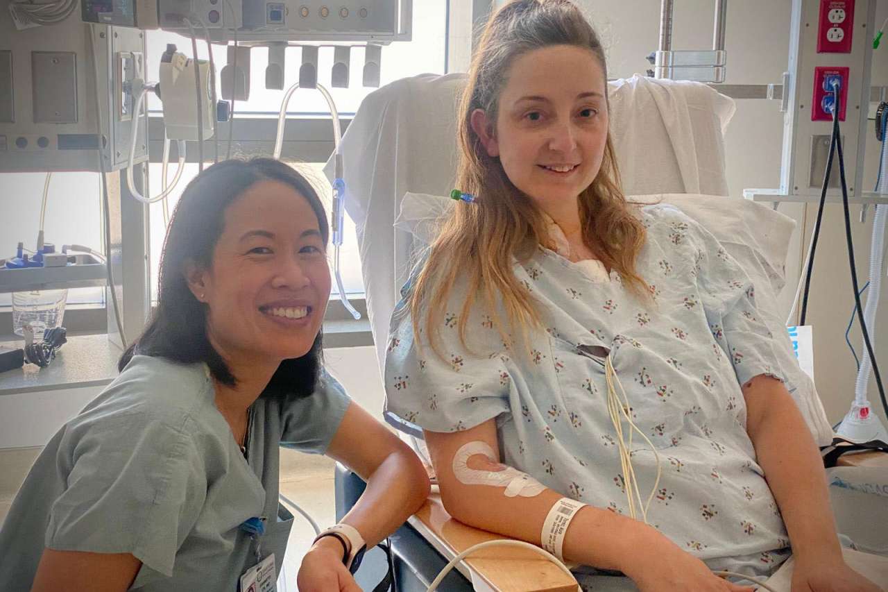 A patient visits with her doctor in her hospital room.