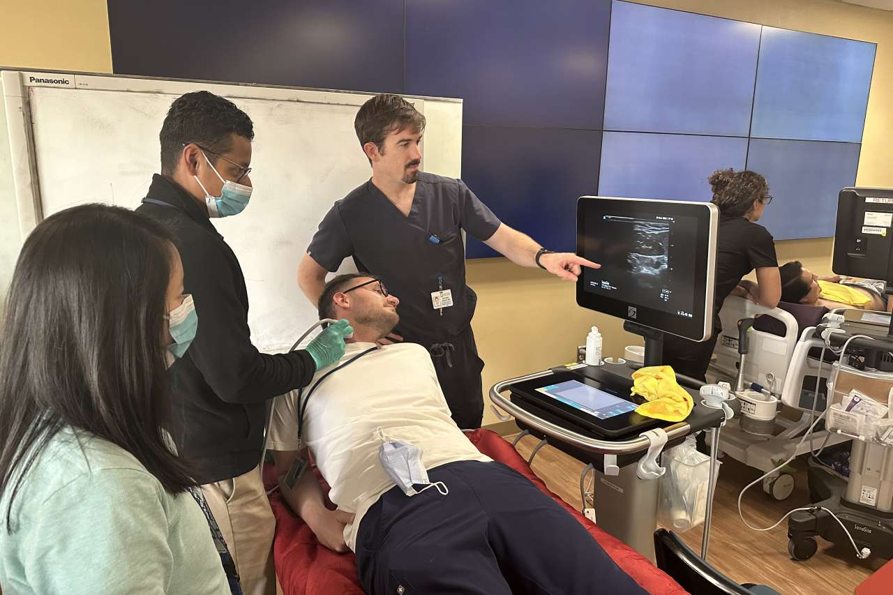 3 students performing an ultrasound on a man's neck