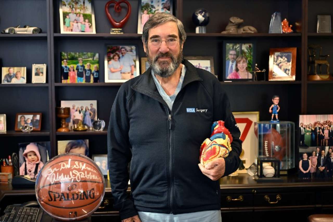 Dr. Shemin smiling at his desk with heart model and basketball