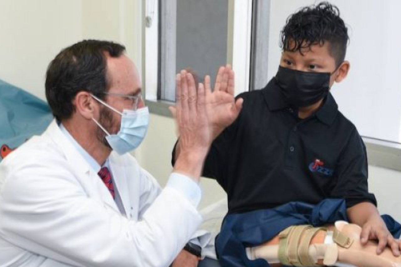 Dr. Anthony Scaduto high-fives Efrain Ordonez Jr during a prosthetic leg fitting after rotationplasty surgery.
