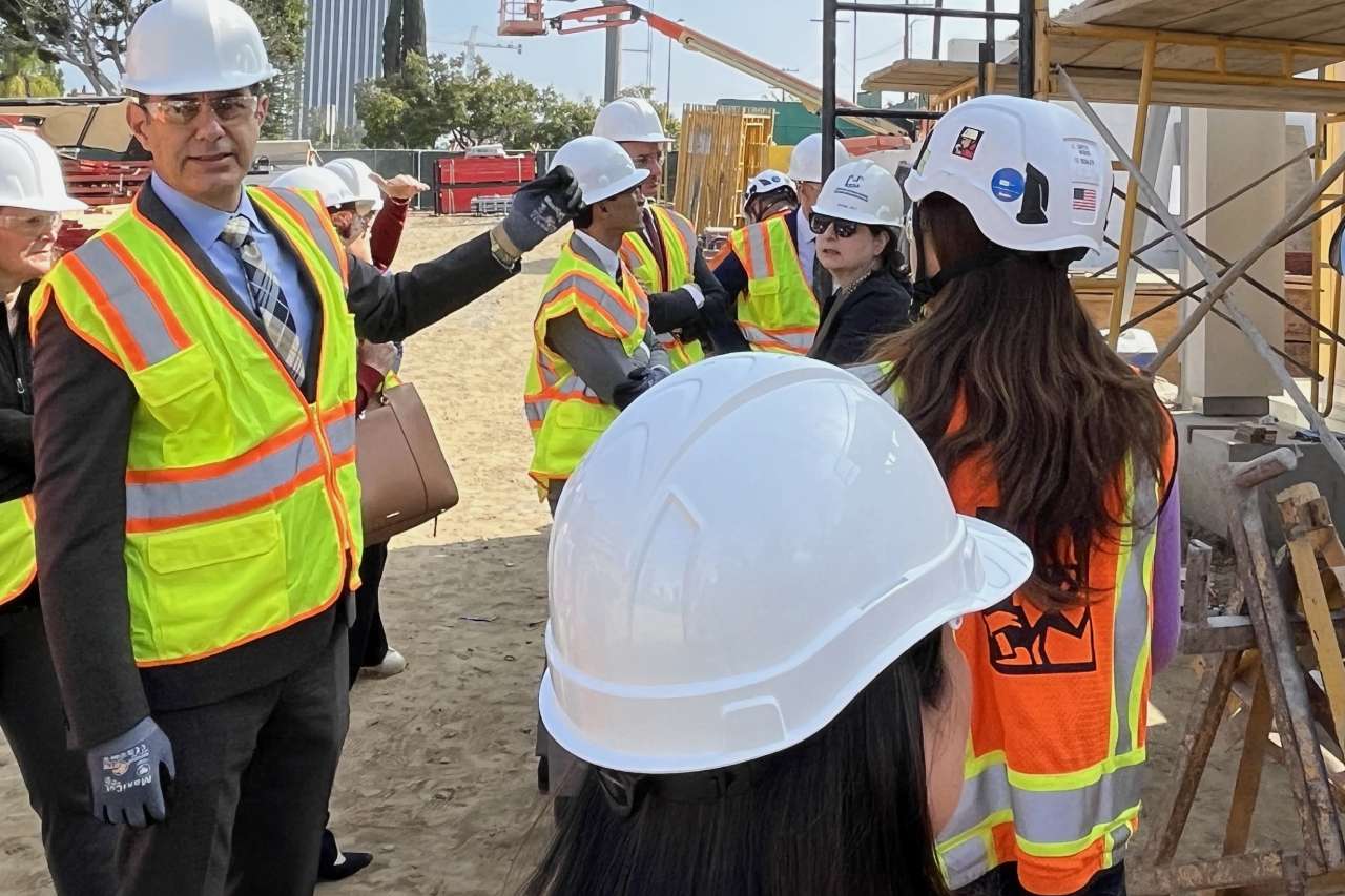 COO Richard Azar and others in hard hats view a mock-up exterior wall at the neuropsychiatric hospital construction site.