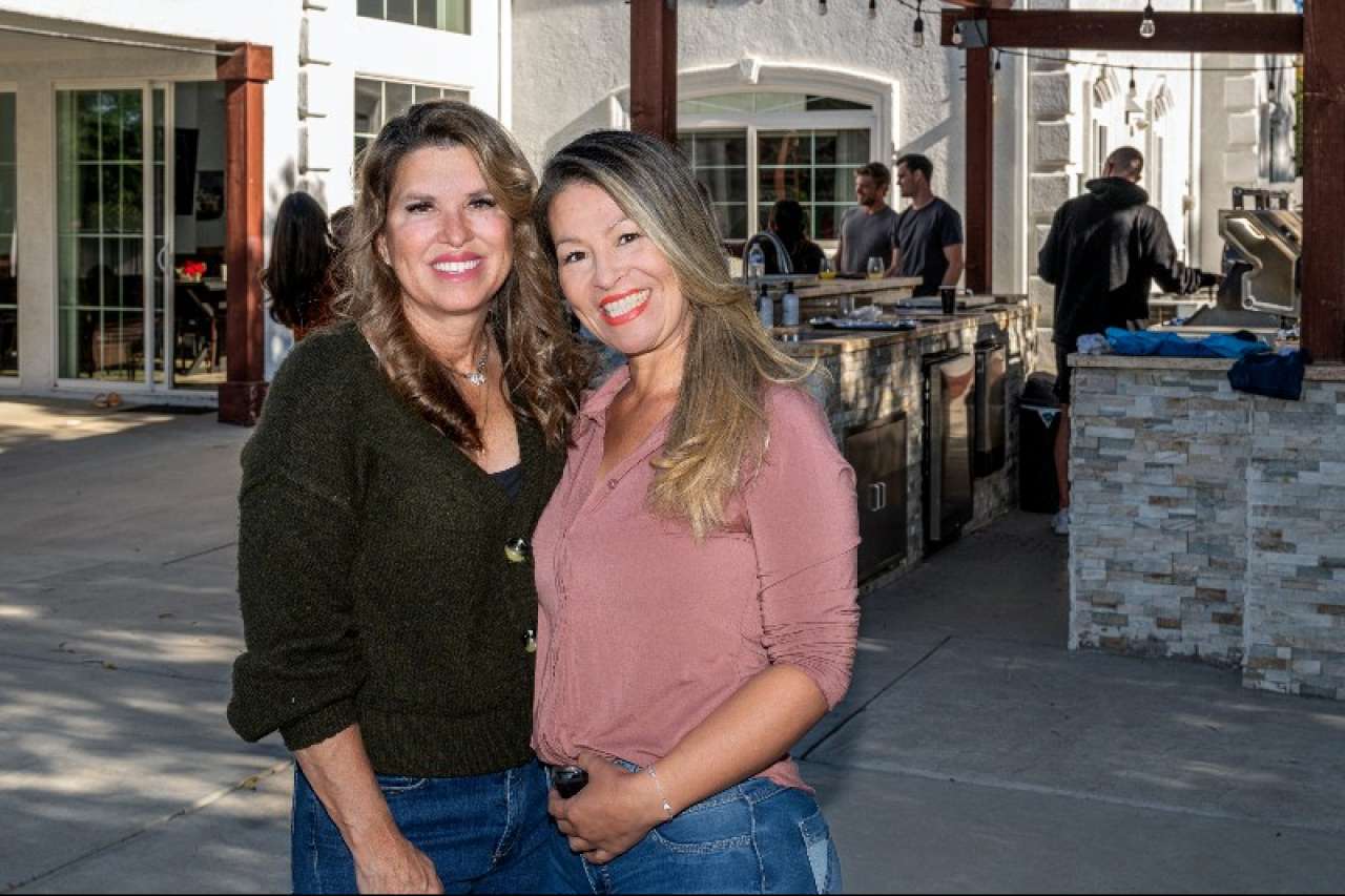 Nanette and Diana at family brunch in an outdoor setting with a patio of other people in the background