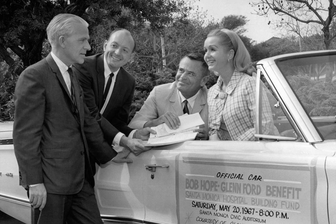 Glen Ford and Debbie Reynolds are in a car promoting a fundraiser.