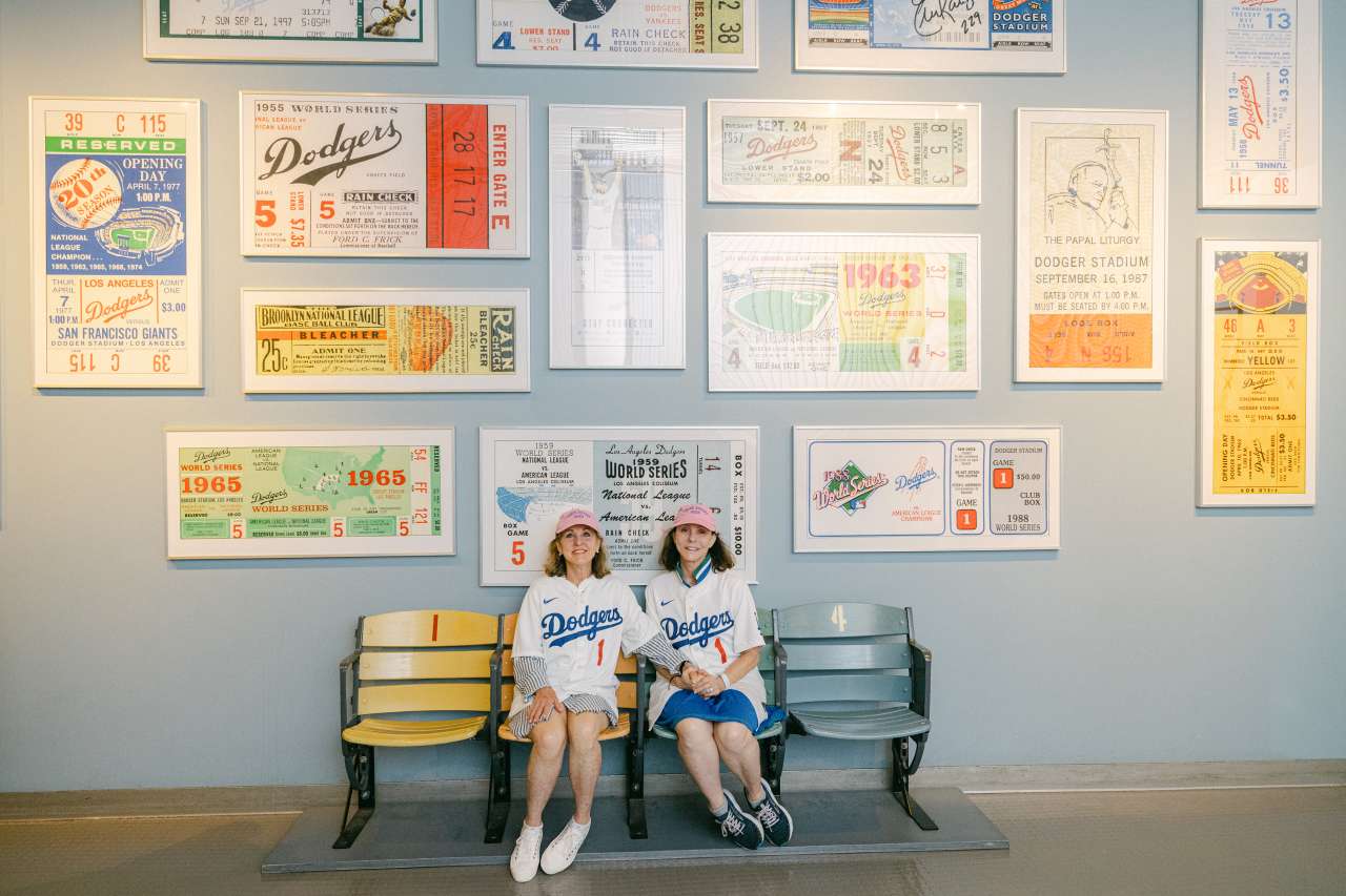 Susan Ford Dorsey and Elisabeth Okun sit next to each other on ballpark seats inside Dodger Stadium.
