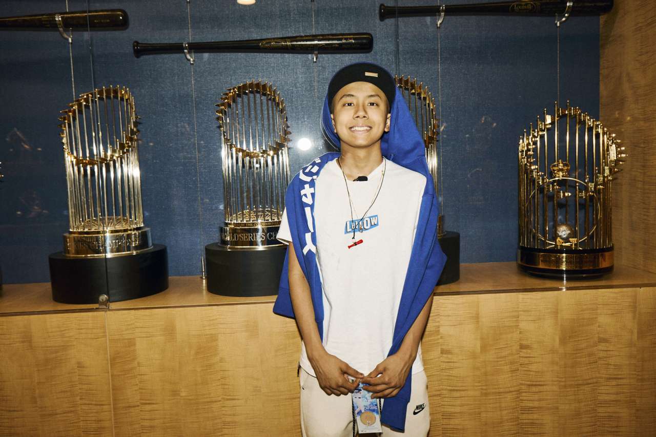 A teen oncology patient stands in front of a trophy case at Dodger Stadium. 