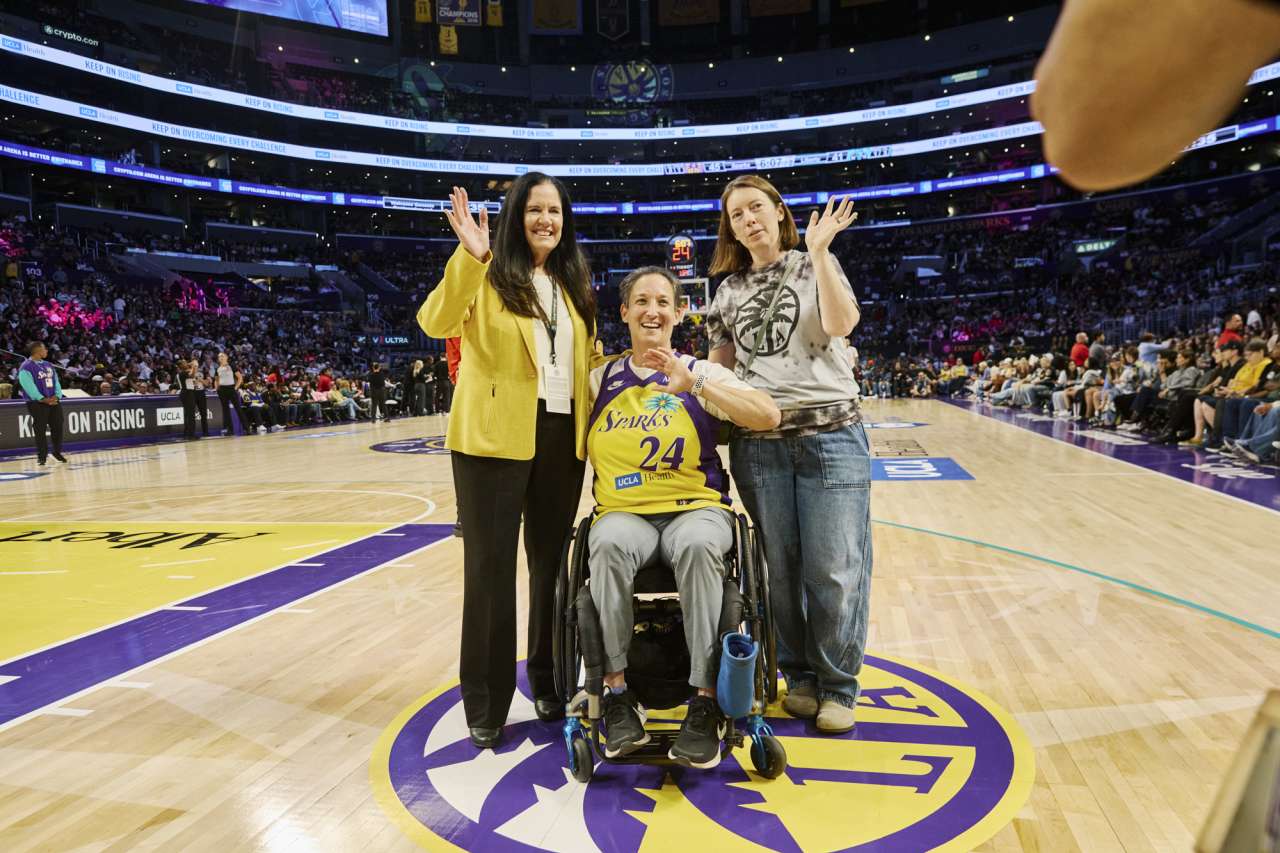 A woman, with fiancee and doctor, is honored on the LA Sparks basketball court.