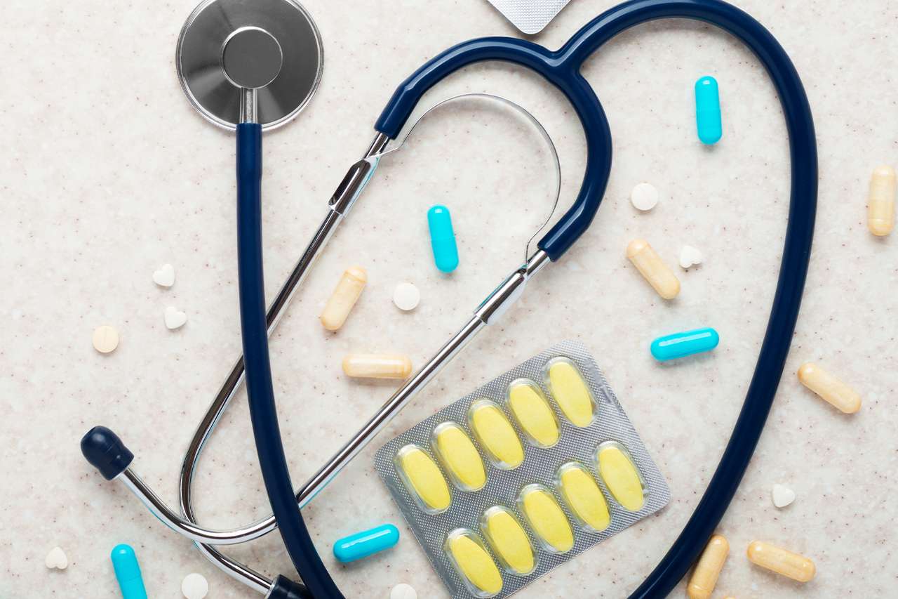 Stethoscope among assorted pills and a blister pack.