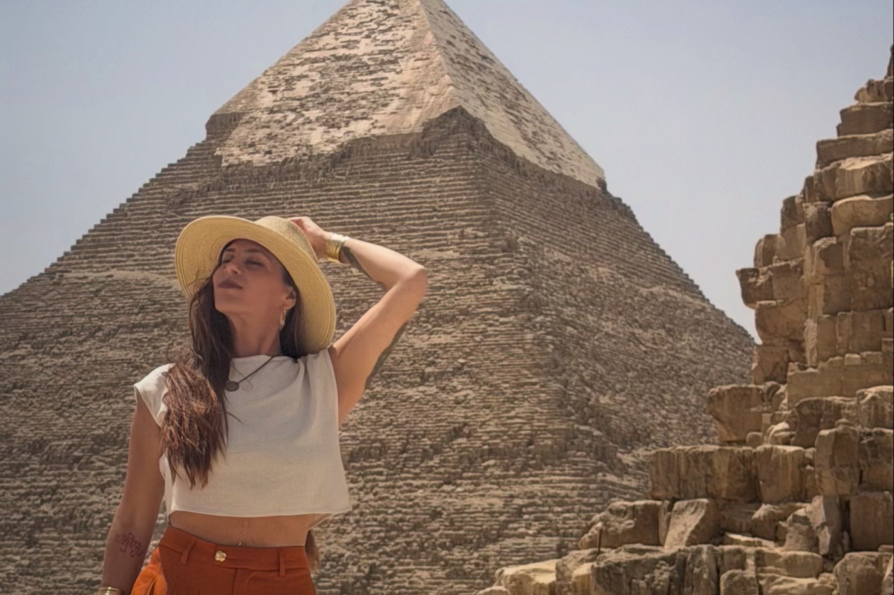 A woman stands in front of a pyramid in Egypt.