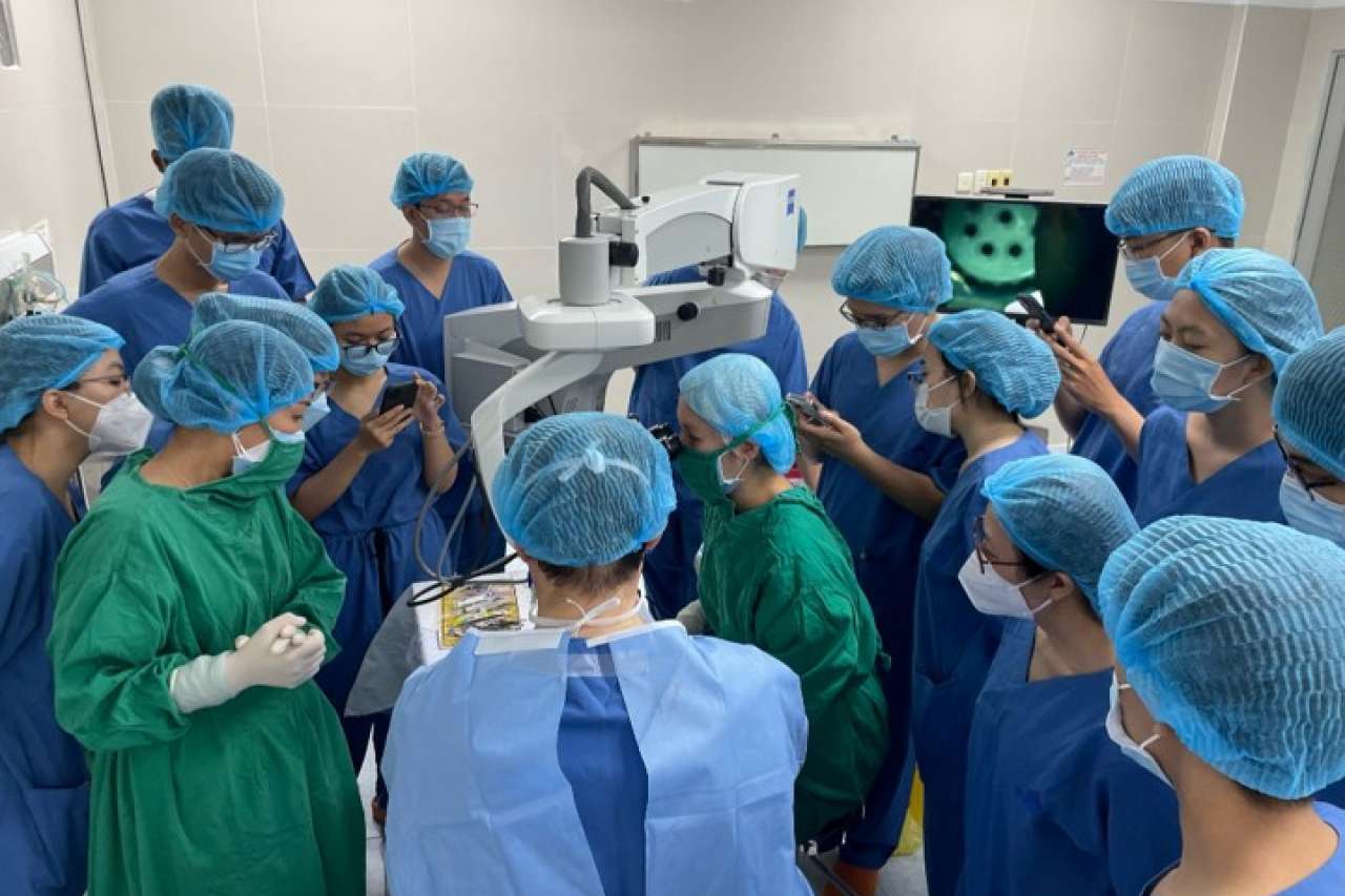A group of ophthalmologists huddles together for a skill transfer session with Dr. Anthony Aldave.