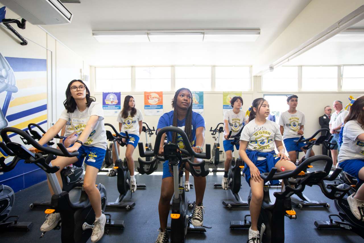 Middle school students ride exercise bikes in a new fitness room