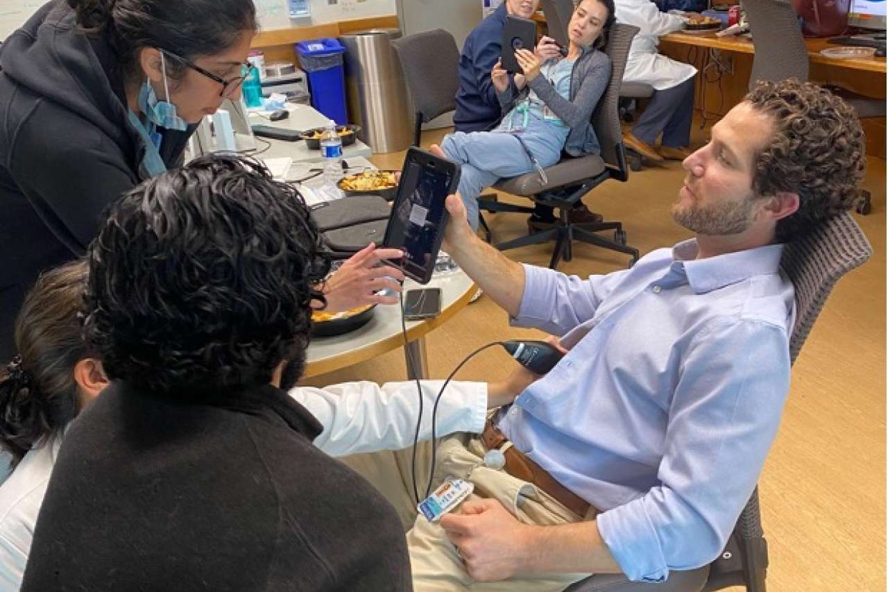 Dr. Kahn performing a training on POCUS in an office surrounded by other physicians